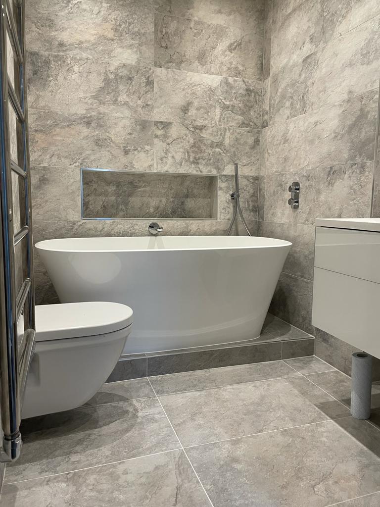 White toilet, basin and bath in grey marble bathroom