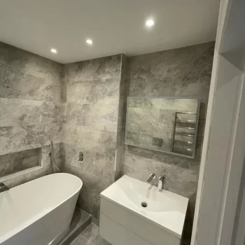 white bath and sink in modern grey bathroom in Richmond, London by Bathroom Inspirations